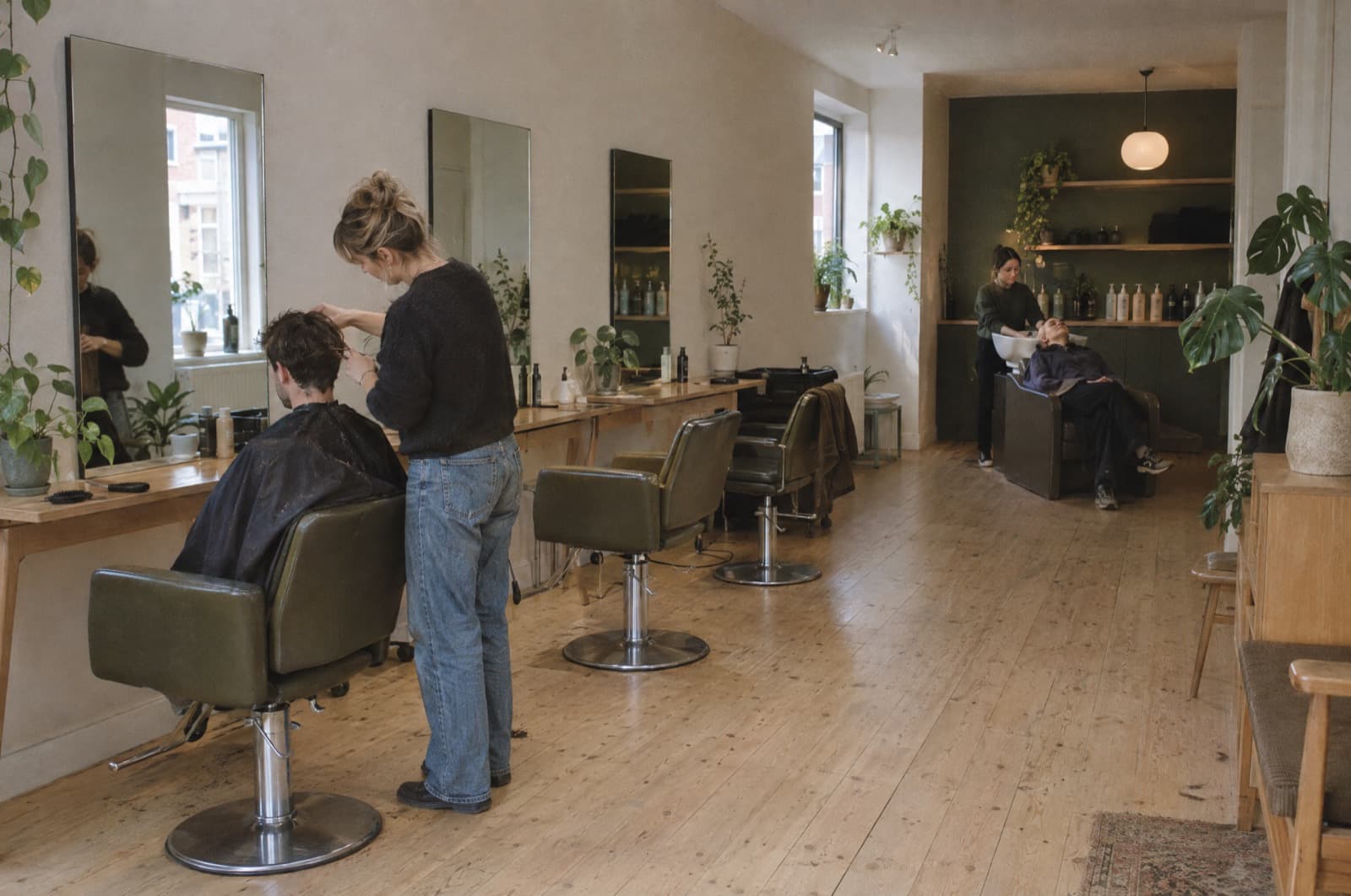 A light salon with three stations, a client at the basin at the back.